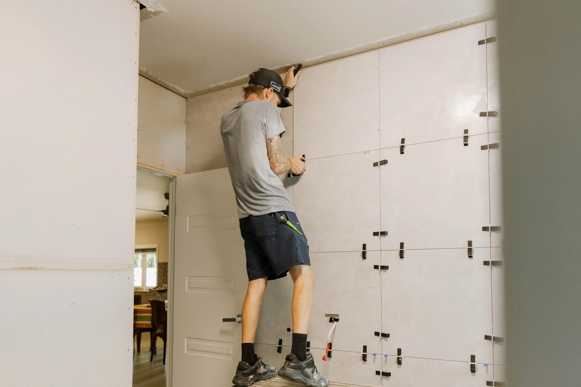 Legacy tradesmen installing large format tiles on a commercial fitout